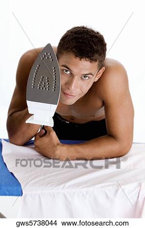 Portrait of a young man holding an iron View Large Photo Image Picture - Portrait of a young man holding an iron. Fotosearch
