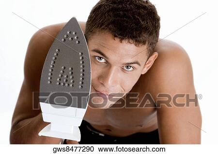 Portrait of a young man holding an iron View Large Photo Image Stock Image - Portrait of a young man holding an iron. Fotosearch