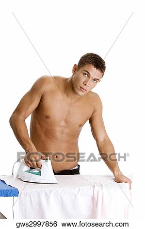 Stock Photograph - Portrait of a young man ironing his shirt. Fotosearch