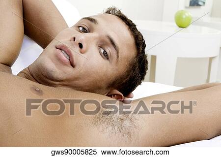 Portrait of a young man lying on a bed View Large Photo Image Stock Photography - Portrait of a young man lying on a bed. Fotosearch