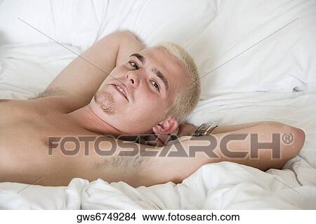 Portrait of a young man lying on the bed View Large Photo Image Picture - Portrait of a young man lying on the bed. Fotosearch