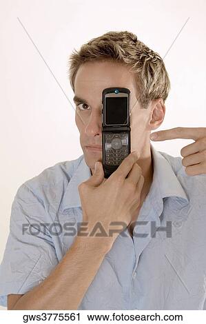 Portrait of a young man pointing to a mobile phone in his hand View Large Photo Image Stock Image - Portrait of a young man pointing to a mobile phone in his hand. Fotosearch