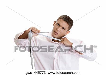 Stock Image - Portrait of a young man pulling his tie. Fotosearch