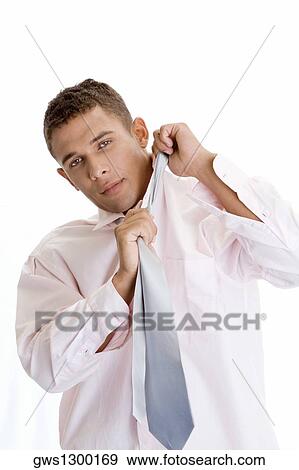 Portrait of a young man pulling his tie View Large Photo Image Stock Photo - Portrait of a young man pulling his tie. Fotosearch
