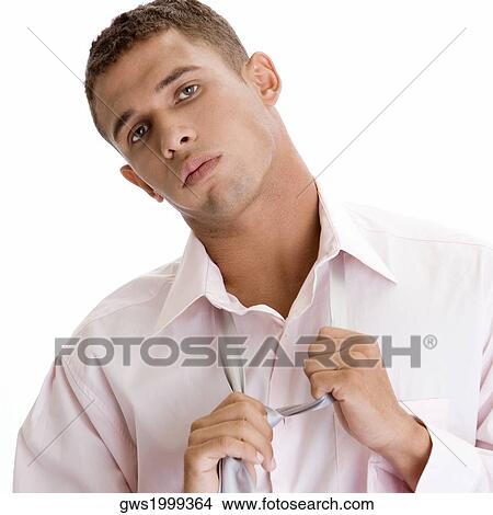 Portrait of a young man removing his tie View Large Photo Image Picture - Portrait of a young man removing his tie. Fotosearch