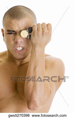 Portrait of a young man squeezing a hand grip in front of his eye View Large Photo Image Stock Photo - Portrait of a young man squeezing a hand grip in front of his eye. Fotosearch