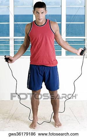 Portrait of a young man standing with a jump rope View Large Photo Image Stock Photograph - Portrait of a young man standing with a jump rope. Fotosearch