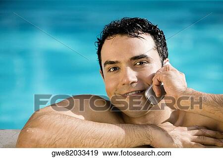 Portrait of a young man talking on a mobile phone in a swimming pool View Large Photo Image Stock Photo - Portrait of a young man talking on a mobile phone in a swimming pool. Fotosearch