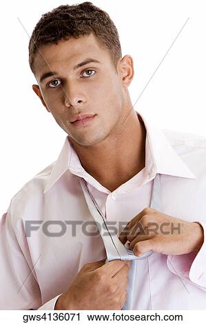 Portrait of a young man tying a necktie View Large Photo Image Stock Image - Portrait of a young man tying a necktie. Fotosearch
