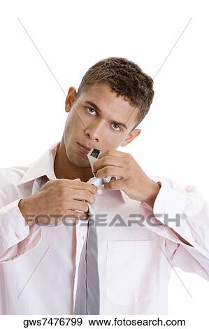 Stock Photo - Portrait of a young man tying a necktie. Fotosearch