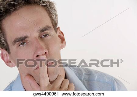 Portrait of a young man with his finger on his lips View Large Photo Image Stock Image - Portrait of a young man with his finger on his lips. Fotosearch
