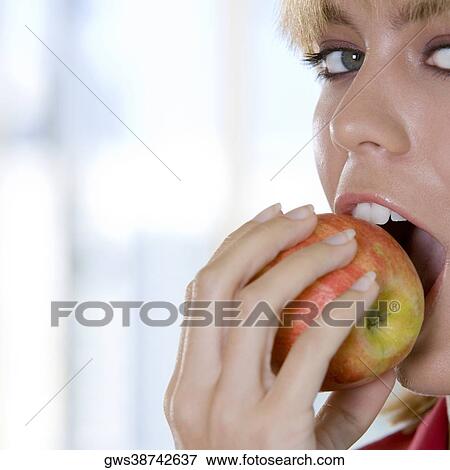 Portrait of a young woman biting an apple View Large Photo Image Stock Photo - Portrait of a young woman biting an apple. Fotosearch