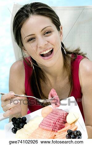 Portrait of a young woman eating fruit salad View Large Photo Image Stock Photograph - Portrait of a young woman eating fruit salad. Fotosearch