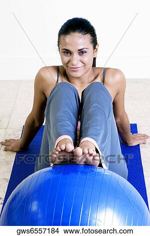 Portrait of a young woman exercising with a fitness ball View Large Photo Image Picture - Portrait of a young woman exercising with a fitness ball. Fotosearch