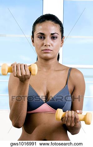 Stock Image - Portrait of a young woman exercising with dumbbells. Fotosearch