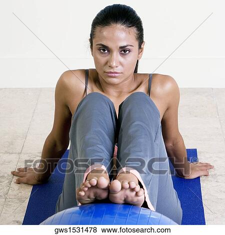 Stock Photo - Portrait of a young woman exercising with a fitness ball. Fotosearch