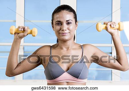 Portrait of a young woman exercising with dumbbells View Large Photo Image Stock Photo - Portrait of a young woman exercising with dumbbells. Fotosearch