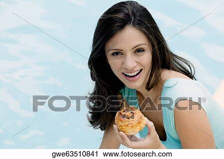 Portrait of a young woman holding a bun View Large Photo Image Stock Image - Portrait of a young woman holding a bun. Fotosearch