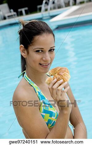 Portrait of a young woman holding a bun close to her mouth View Large Photo Image Stock Image - Portrait of a young woman holding a bun close to her mouth. Fotosearch