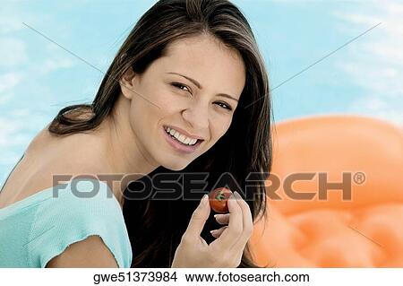 Picture - Portrait of a young woman holding a tomato. Fotosearch