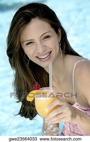 Portrait of a young woman holding a glass of juice View Large Photo Image Stock Image - Portrait of a young woman holding a glass of juice. Fotosearch