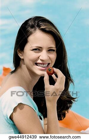 Portrait of a young woman holding a tomato View Large Photo Image Stock Photo - Portrait of a young woman holding a tomato. Fotosearch