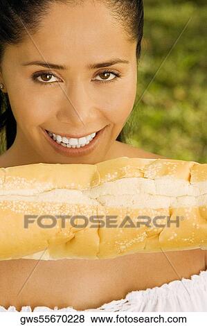 Portrait of a young woman holding a loaf of bread View Large Photo Image Stock Photo - Portrait of a young woman holding a loaf of bread. Fotosearch
