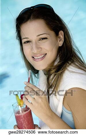 Stock Photograph - Portrait of a young woman holding a glass of juice. Fotosearch
