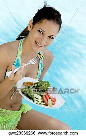 Stock Photograph - Portrait of a young woman holding a plate of salad. Fotosearch