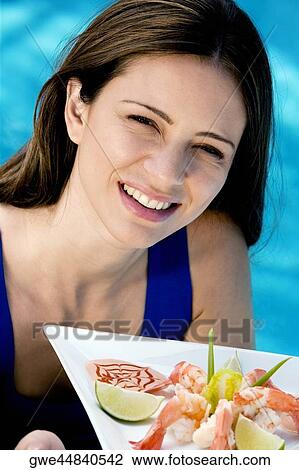 Stock Image - Portrait of a young woman holding a tray. Fotosearch