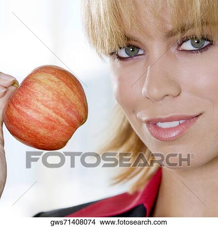 Portrait of a young woman holding an apple View Large Photo Image Picture - Portrait of a young woman holding an apple. Fotosearch