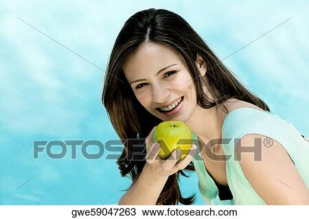 Portrait of a young woman holding an apple View Large Photo Image Stock Image - Portrait of a young woman holding an apple. Fotosearch