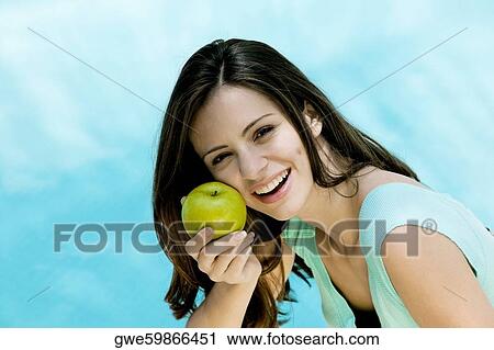Portrait of a young woman holding an apple View Large Photo Image Stock Image - Portrait of a young woman holding an apple. Fotosearch