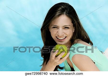 Portrait of a young woman holding an apple View Large Photo Image Stock Image - Portrait of a young woman holding an apple. Fotosearch