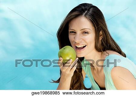 Stock Photography - Portrait of a young woman holding an apple. Fotosearch