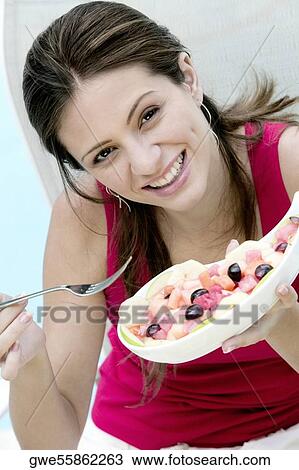 Stock Image - Portrait of a young woman holding food in a bowl. Fotosearch