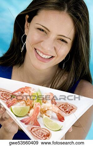 Portrait of a young woman holding food in a tray View Large Photo Image Stock Photo - Portrait of a young woman holding food in a tray. Fotosearch