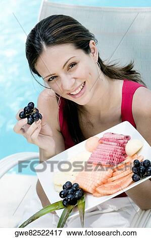 Portrait of a young woman holding food in a tray View Large Photo Image Stock Photo - Portrait of a young woman holding food in a tray. Fotosearch