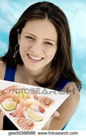 Portrait of a young woman holding food in a tray View Large Photo Image Stock Photograph - Portrait of a young woman holding food in a tray. Fotosearch