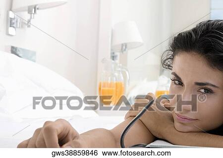 Portrait of a young woman lying on a bed View Large Photo Image Stock Photograph - Portrait of a young woman lying on a bed. Fotosearch