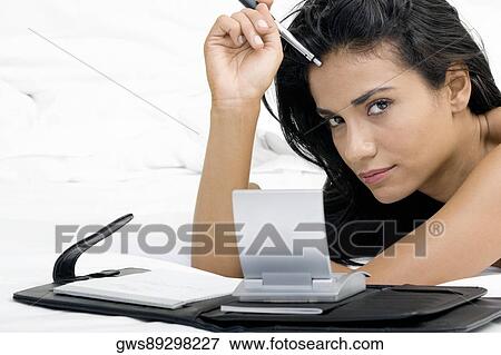 Portrait of a young woman lying on a bed in front of a personal organizer View Large Photo Image Stock Photo - Portrait of a young woman lying on a bed in front of a personal organizer. Fotosearch