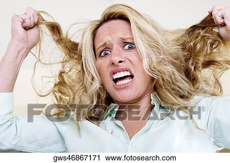 Stock Image - Portrait of a young woman pulling her hair. Fotosearch