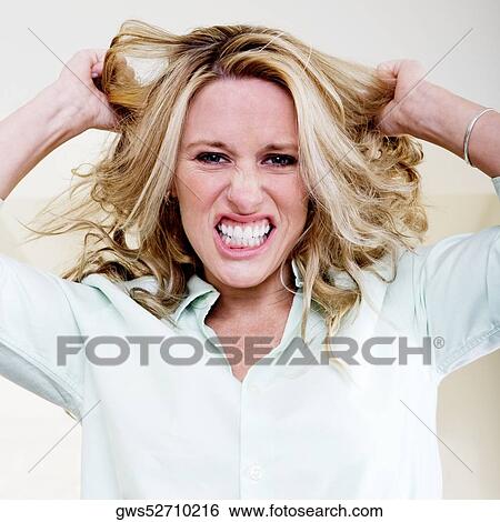 Portrait of a young woman pulling her hair and clenching her teeth View Large Photo Image Stock Photograph - Portrait of a young woman pulling her hair and clenching her teeth. Fotosearch