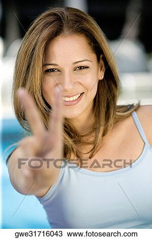 Portrait of a young woman showing a peace sign View Large Photo Image Stock Image - Portrait of a young woman showing a peace sign. Fotosearch