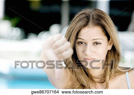 Portrait of a young woman showing thumbs down View Large Photo Image Picture - Portrait of a young woman showing thumbs down. Fotosearch