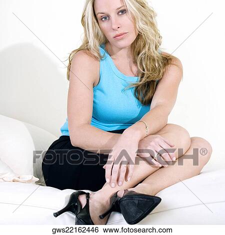 Portrait of a young woman sitting on a couch View Large Photo Image Stock Photograph - Portrait of a young woman sitting on a couch. Fotosearch