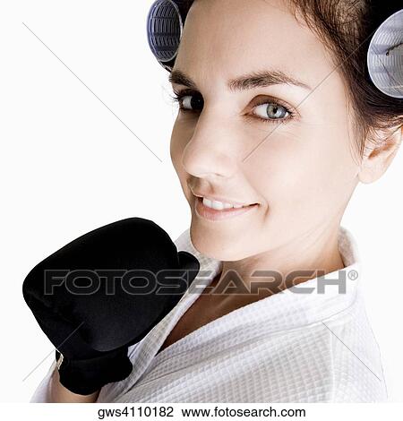 Stock Image - Portrait of a young woman wearing a boxing glove. Fotosearch