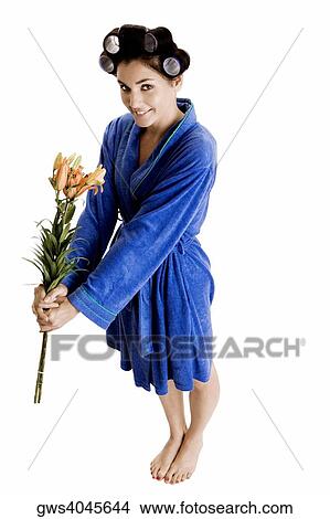 Picture - Portrait of a young woman with curlers in her hair holding flowers. Fotosearch