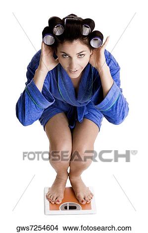 Portrait of a young woman with curlers in her hair standing on a weight scale View Large Photo Image Picture - Portrait of a young woman with curlers in her hair standing on a weight scale. Fotosearch