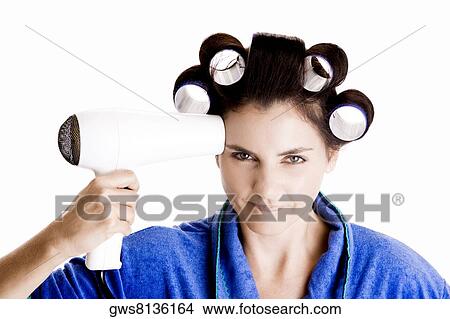 Portrait of a young woman with curlers in her hair holding a hairdryer View Large Photo Image Picture - Portrait of a young woman with curlers in her hair holding a hairdryer. Fotosearch